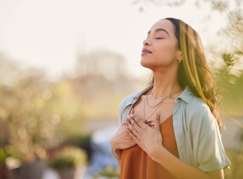 Woman with eyes closed and hands over heart breathing - Paul Wagner