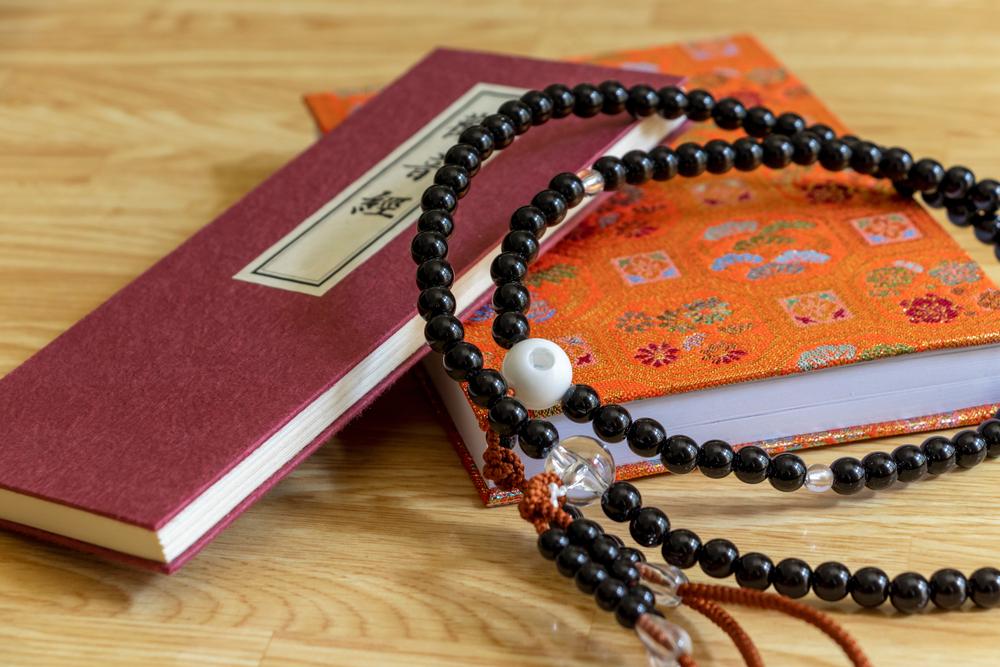 A scripture book of the Heart Sutra with prayer beads resting gently across its pages, symbolizing Buddhist wisdom, emptiness, and compassion.