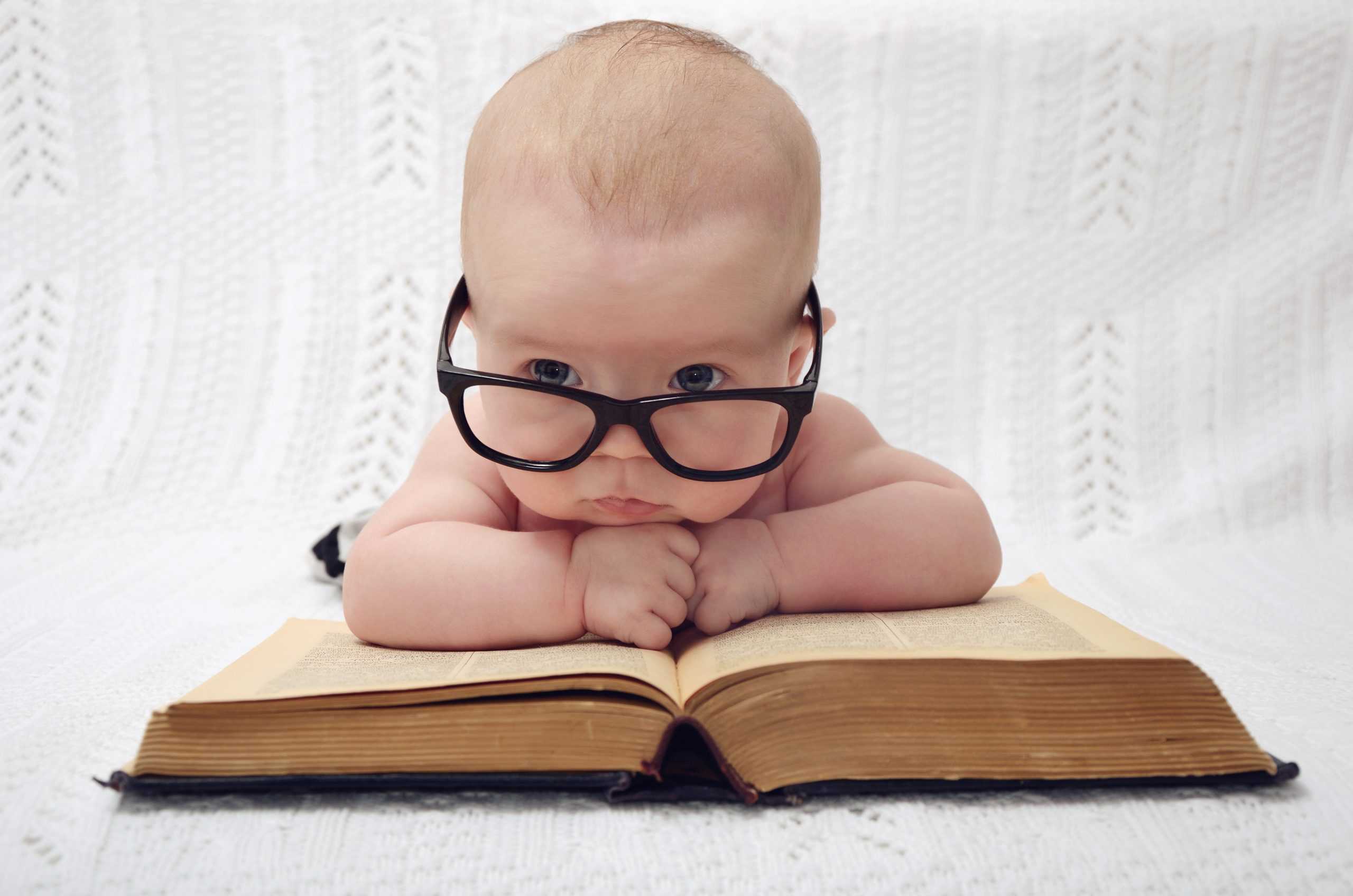 Baby with glasses looking at book - Paul Wagner
